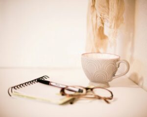 Silent Medicine — warm mug, journal, pen, and scarf in soft neutral light.