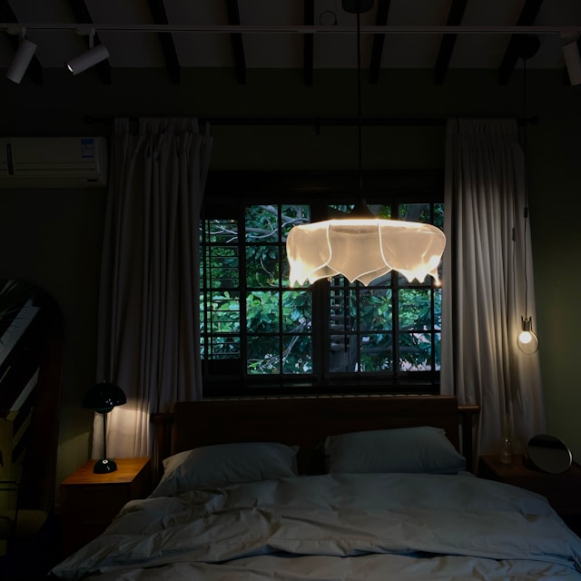 Calm bedroom at dusk with a soft warm bedside lamp... quiet, restful atmosphere.