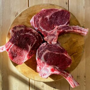 Silent Medicine — three raw bone-in beef cuts on a wooden board, neutral daylight.
