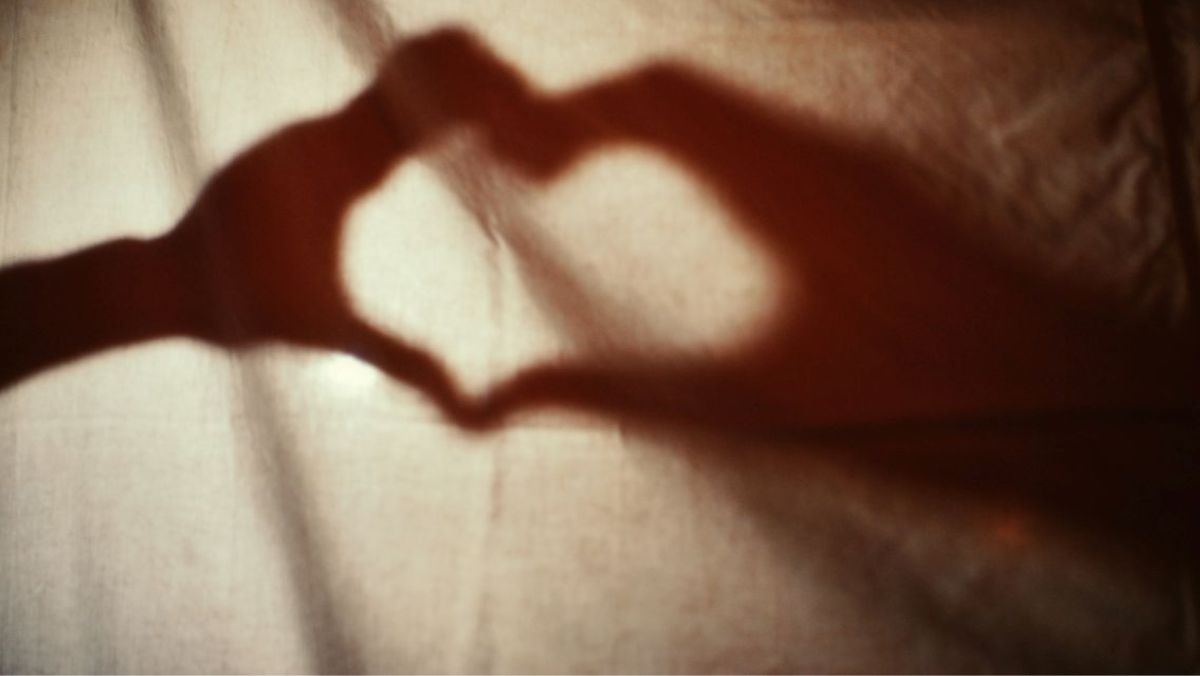Soft shadow of hands forming a heart on fabric, suggesting a calm, coherent rhythm of breath and heartbeat.