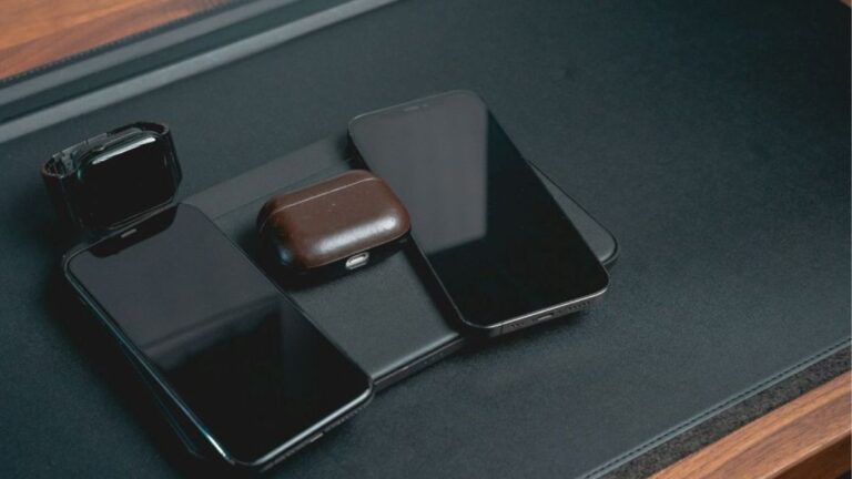 Phones and earbuds parked on a charging pad in a small tray... visual cue to end evening checks and sleep better.