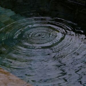 Concentric ripples spreading across a blue-green pool, light reflecting—evoking calm and nervous-system balance.