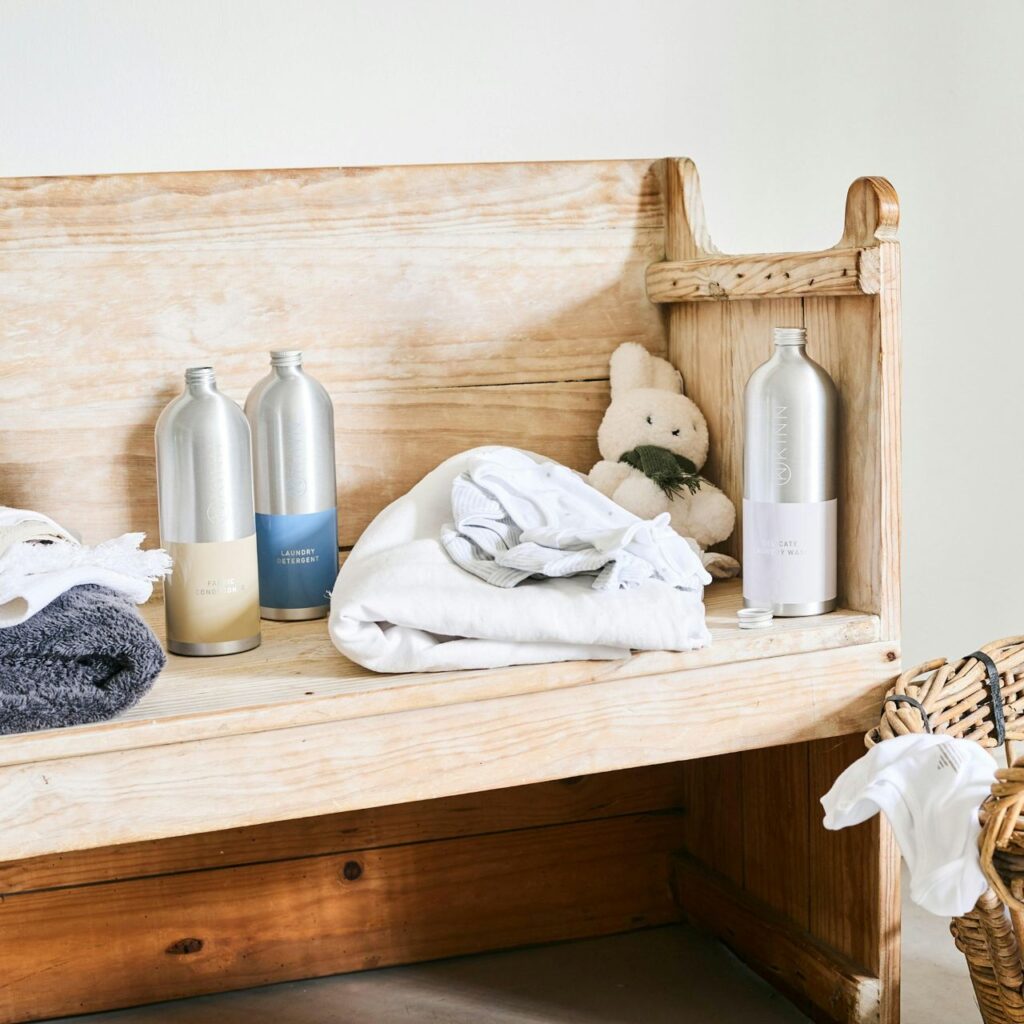 Folded white towel with a stainless bottle on a wooden bench.