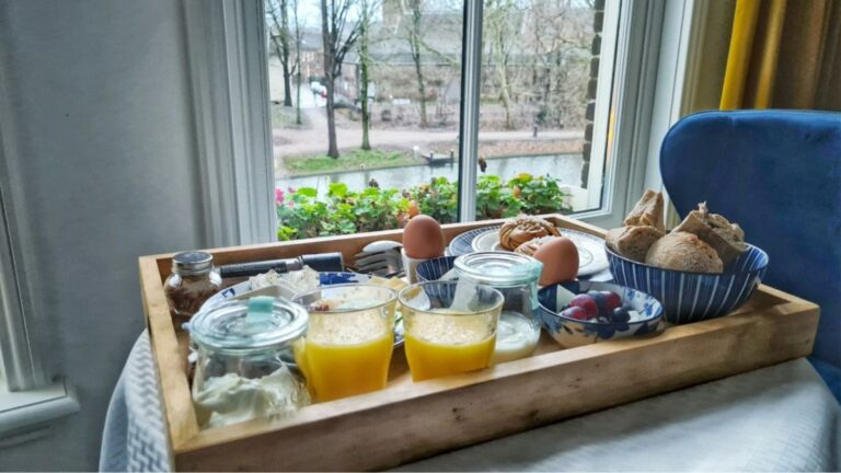 Tray with real food and drinks by a bright window—morning daylight, water, eggs, yogurt, fruit... quiet cues for calm daily inputs.