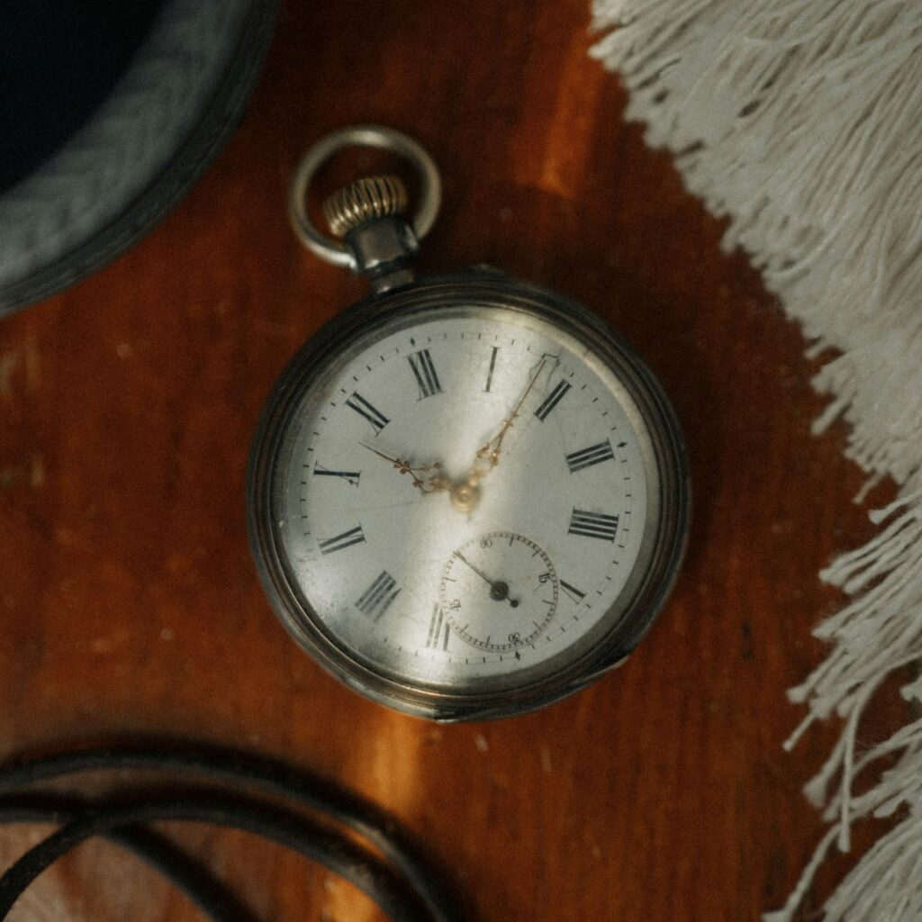 Antique pocket watch on a wooden table with soft light.
