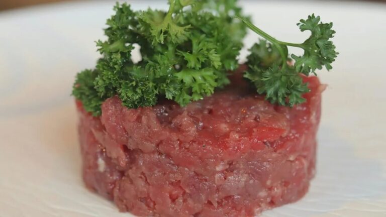 Raw ground beef formed into a round, topped with curly parsley.