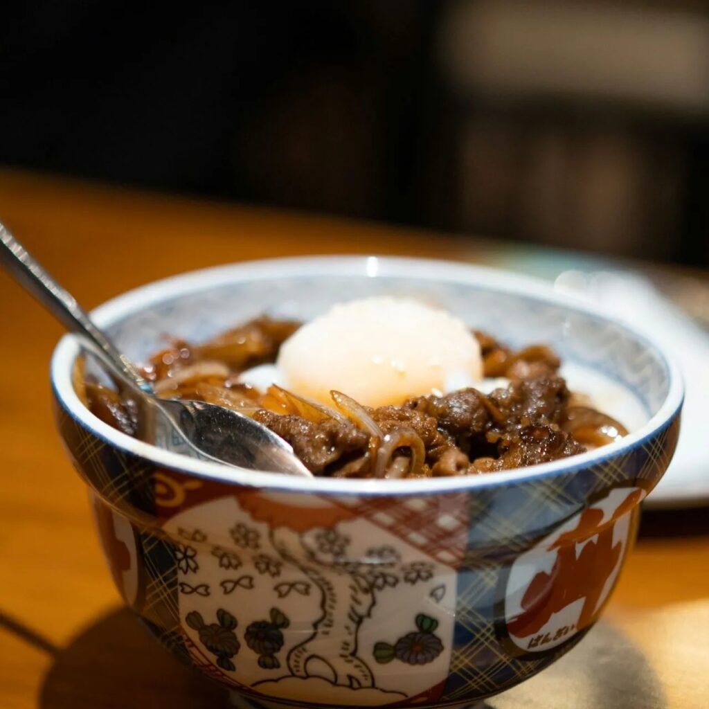 Warm ground beef in patterned bowl with a soft egg on top.