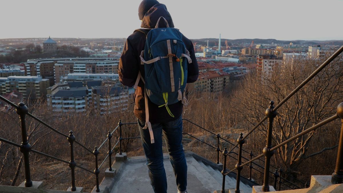 Person with a backpack walking up city steps at sunrise, showing relaxed shoulders and an easy, steady pace.