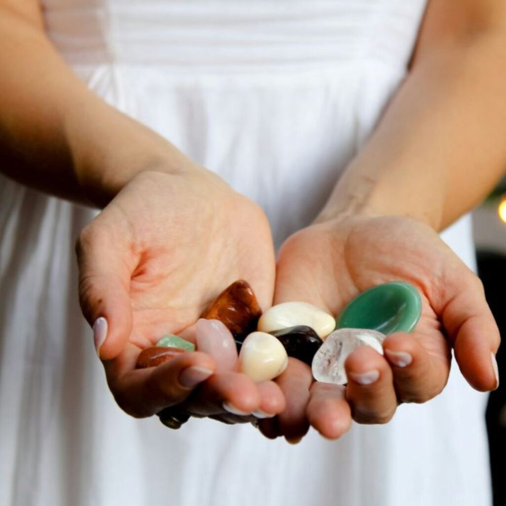 Person in a white dress holding a handful of polished crystals