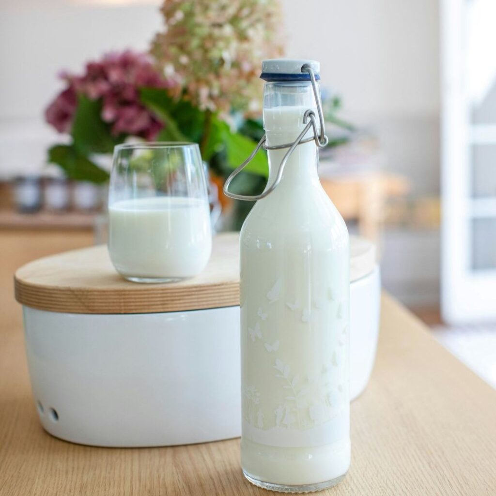 Glass and swing-top bottle of milk on a wooden table with a soft indoor background