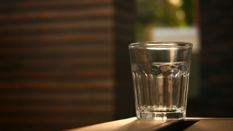 Glass of drinking water in warm natural light on a wooden surface