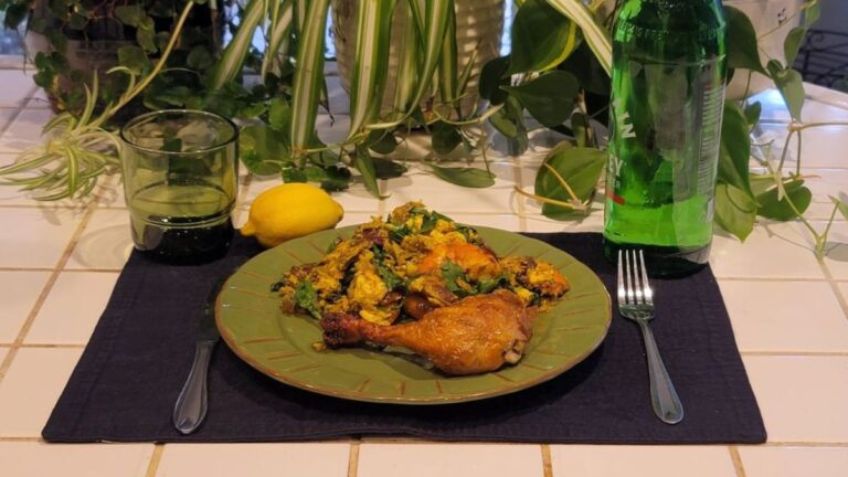 Cooked ketovore meal with roasted chicken drumstick, eggs, arugula, shrimp, and lemon on a plate