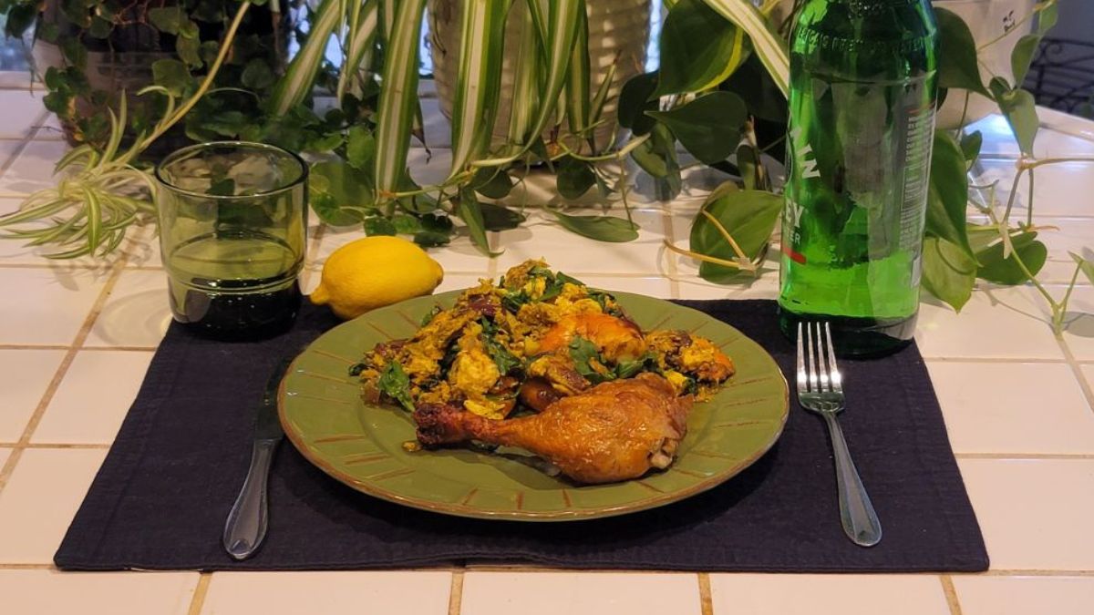 Cooked ketovore meal with roasted chicken drumstick, eggs, arugula, shrimp, and lemon on a plate